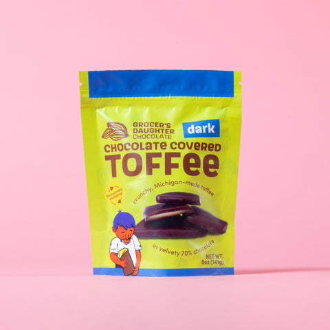 Packaging of Grocer's Daughter Dark Chocolate Covered Toffee on a pink background