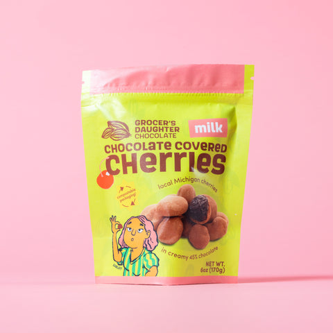 Packaging of Grocer's Daughter Milk Chocolate Covered Cherries on a pink background